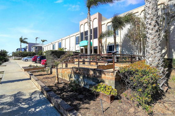 Front view of a two-story building with an entrance ramp and surrounding bushes.
