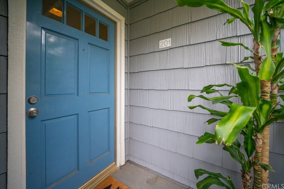 Front view of a blue door with house number 201 and gray siding.