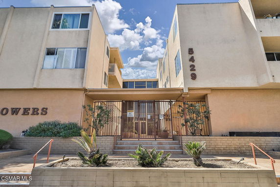 Front view of a multi-story building with balconies and a gated entrance.