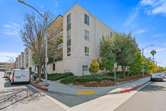 Front view of a multi-story condominium building on a street corner.