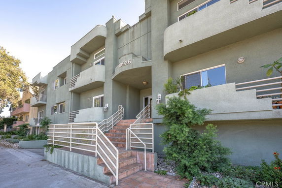Front view of a multi-story building with balconies and stair entrance.