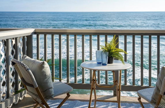 View of the ocean seen from a balcony with a table and chairs.