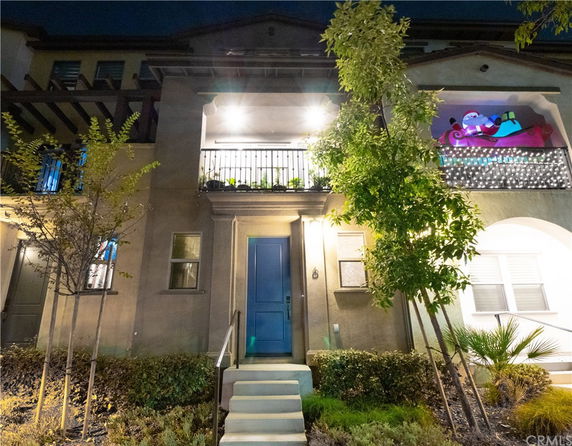 Front view of a multi-story house with a balcony and decorative lighting.