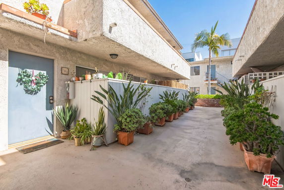 Front view of a multi-story residential building with balconies and potted plants.