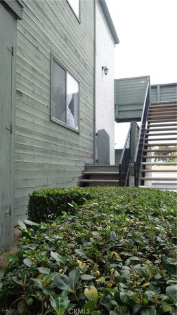 Side view of a residential building with green wooden siding and an outdoor staircase.