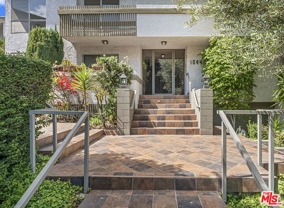 Front view of a house entrance with tiled steps and a garden.