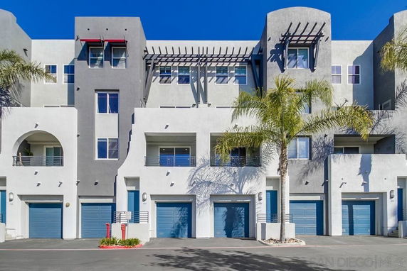 Front view of a multi-story residential building with blue garage doors and balconies.