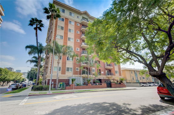 Front view of a multi-story apartment building with palm trees.