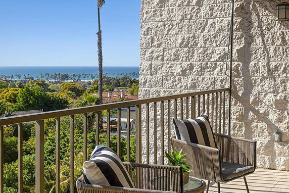 Balcony with chairs and ocean view in the background.