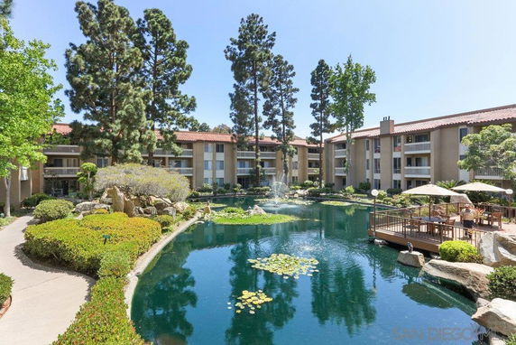 View of residential buildings with water feature and lush greenery.