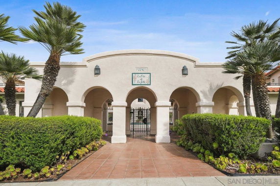 Front view of a building with an arched entrance and palm trees.