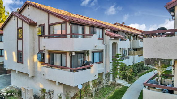 Front view of a multi-story residential building with balconies and red roof.