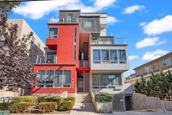 Front view of a modern multi-story building with red and gray facade.
