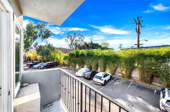 View of an outdoor parking area with several cars and nearby greenery.