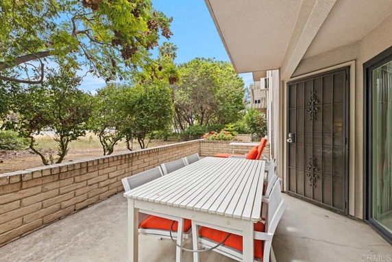 Outdoor patio area with a white table and chairs next to a building entrance.
