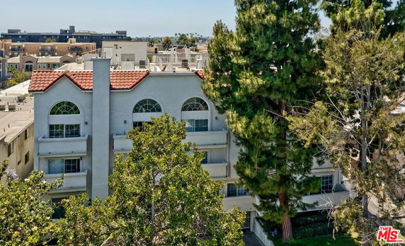 Front view of a multi-story building with a red-tiled roof and large arched windows.