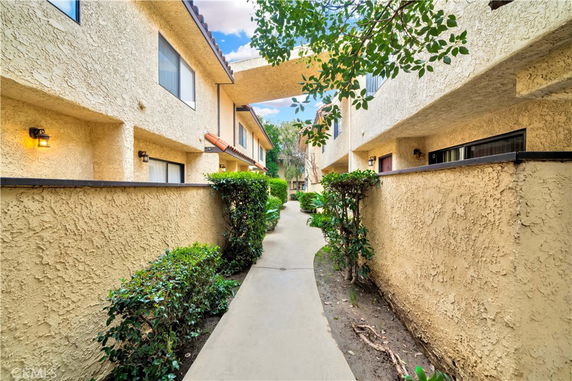 Front view of an apartment building with stucco walls and pathway.