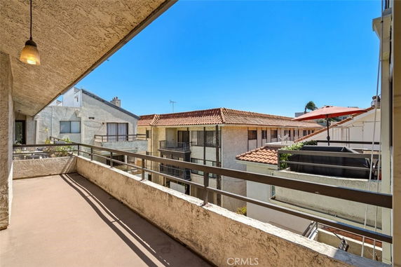 Balcony view of adjacent apartment buildings with tiled roofs and clear sky.