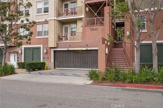 Front view of a multi-story apartment building with stairs and a garage.