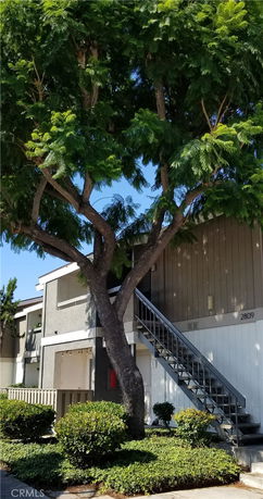 Elevated view of a building with external stairs and a tree in front.