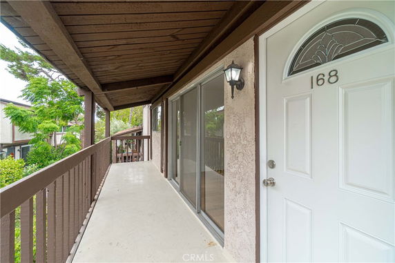 Exterior view of a building entrance with a white door and a covered walkway.