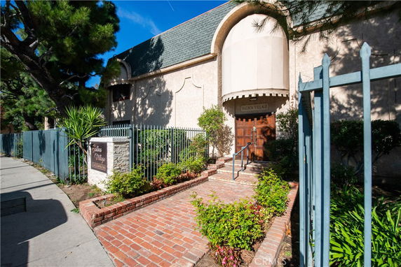 Front view of a building with an arched entrance and a sign reading 'Balboa Village Condominiums' next to it.