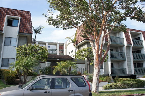 Front view of a multi-story residential building with balconies and a car parked in front.