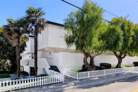 Front view of a multi-story building with a white picket fence.