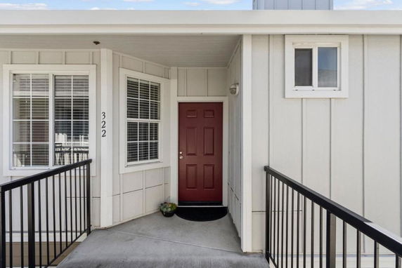 Front view of a house with a red door and white siding.