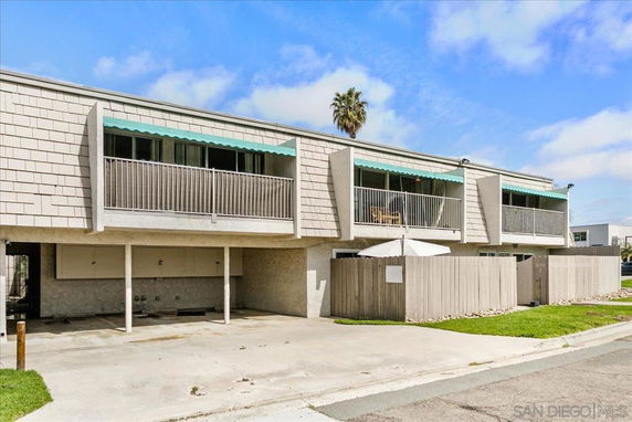 Front view of a two-story building with balconies and a parking area underneath.