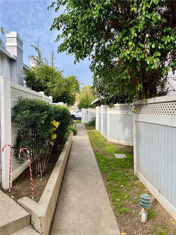 Pathway between residential fences with trees and shrubs on both sides.
