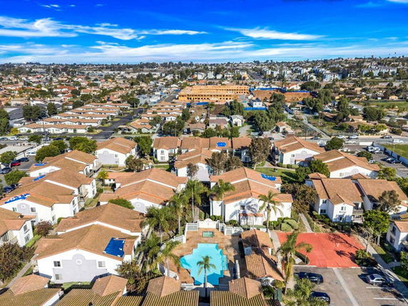Wide-angle aerial view of a residential neighborhood with multiple houses and a central swimming pool.