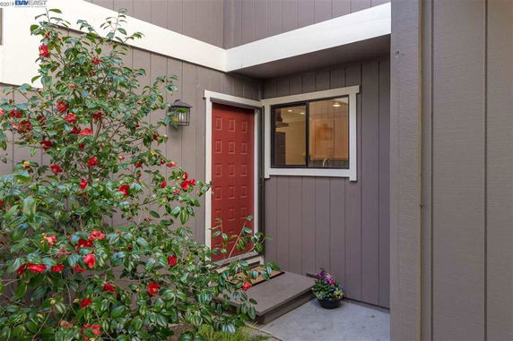 Front view of a house with a red door and adjacent window.