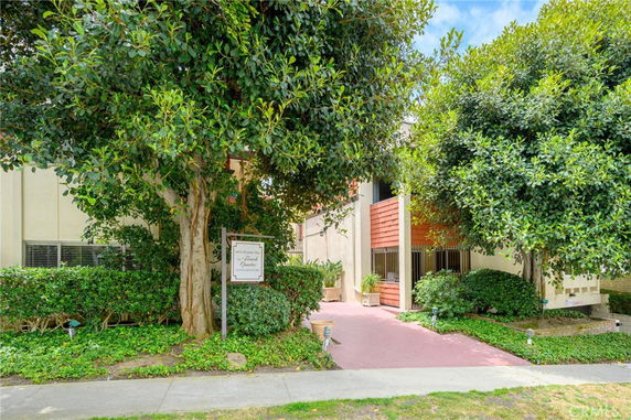 Front view of a condominium building with trees and shrubs around the entrance.