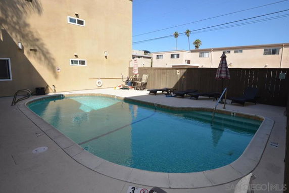 Outdoor swimming pool area with lounge chairs and an umbrella.