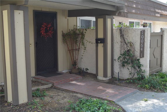 Entryway of a house with a decorative door and brick walkway.