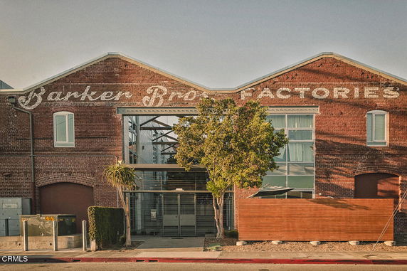 Front view of a brick factory building with large windows and 'Barker Bros Factories' written on it.