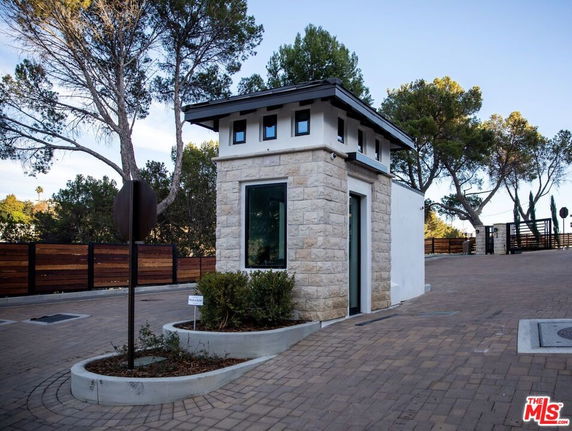 Small stone building with modern design and glass window, situated near a driveway.