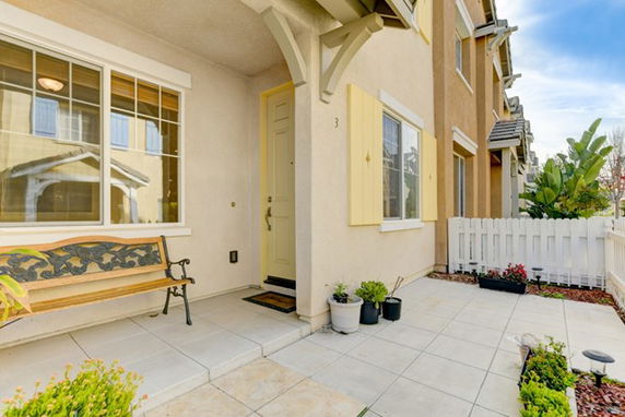 Front view of a multi-story townhouse with a small porch and decorative bench.
