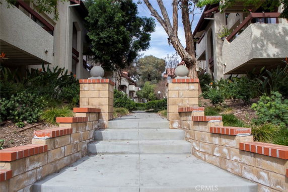 Front view of a multi-story building with a landscaped entrance and brick pillars.