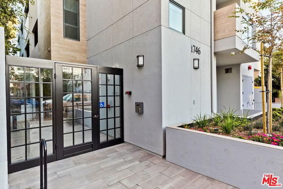 Front view of a modern building entrance with glass doors and polished stone walkway.