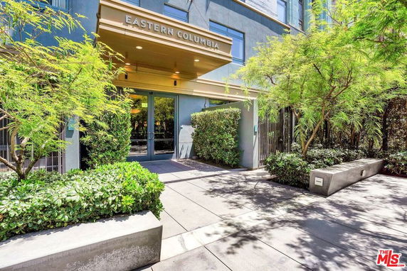 Front view of a building entrance with a canopy and surrounding greenery.