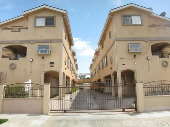 Front view of a multi-story apartment complex with gated entrance.