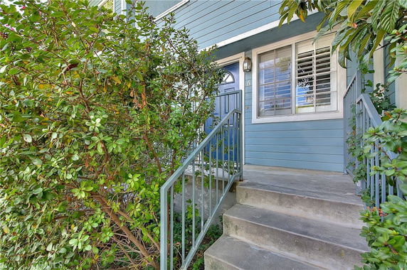 Front view of a house entrance with blue siding and a staircase leading to a blue door.