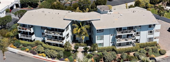 Front view of a multi-story apartment building with balconies and surrounding landscaping.