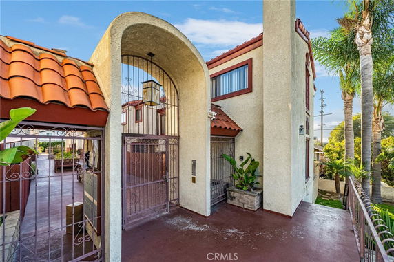 Front view of a multi-story house with an arched entrance and tiled roof.