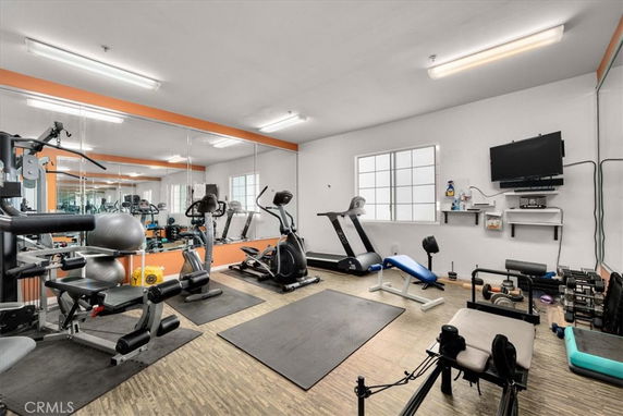 Indoor gym with exercise equipment and mirrored walls.