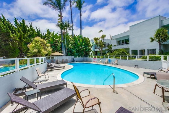 Outdoor swimming pool area with lounge chairs and surrounding greenery.
