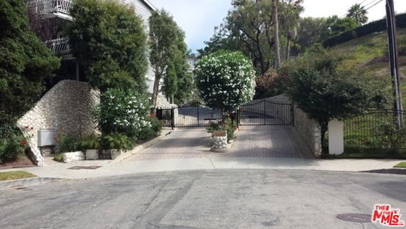 Front view of a gated driveway with stone walls and trees