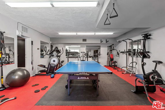 Indoor recreation area with exercise equipment and a table tennis table.